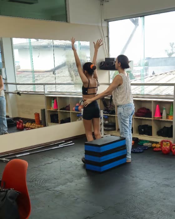Paciente alongando os braços para cima com a Giovana ao lado